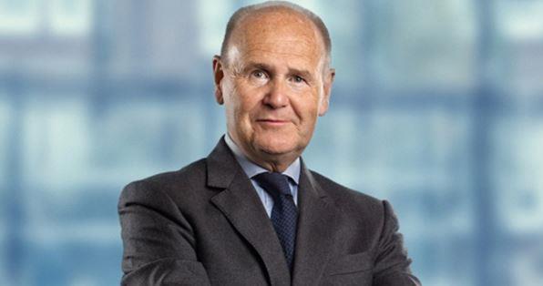 Man wearing suit with crossed arms and a smile looks towards the camera